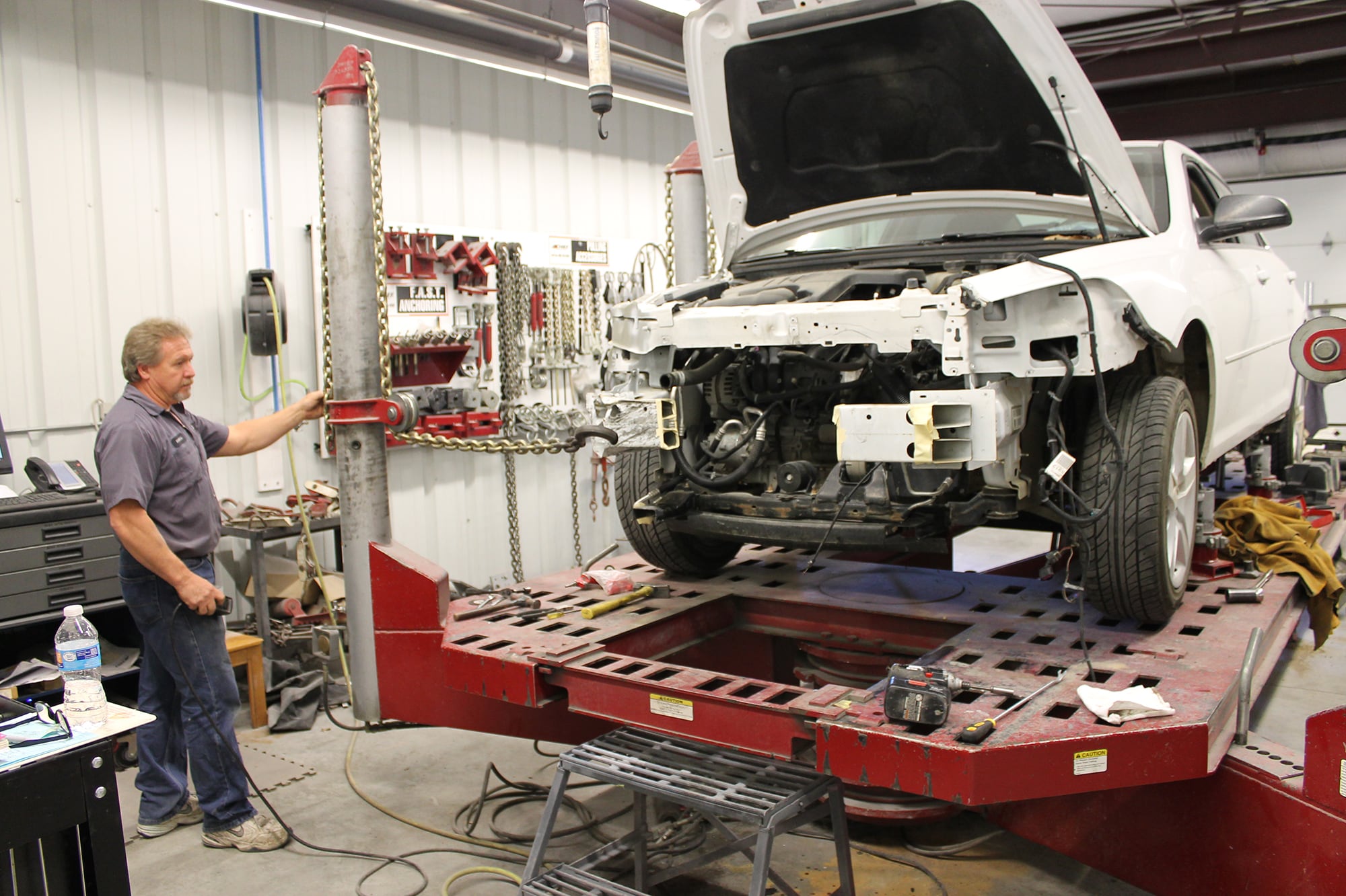 A technician measuring a vehicle on the frame rack at Rusty Drewing Collision Center